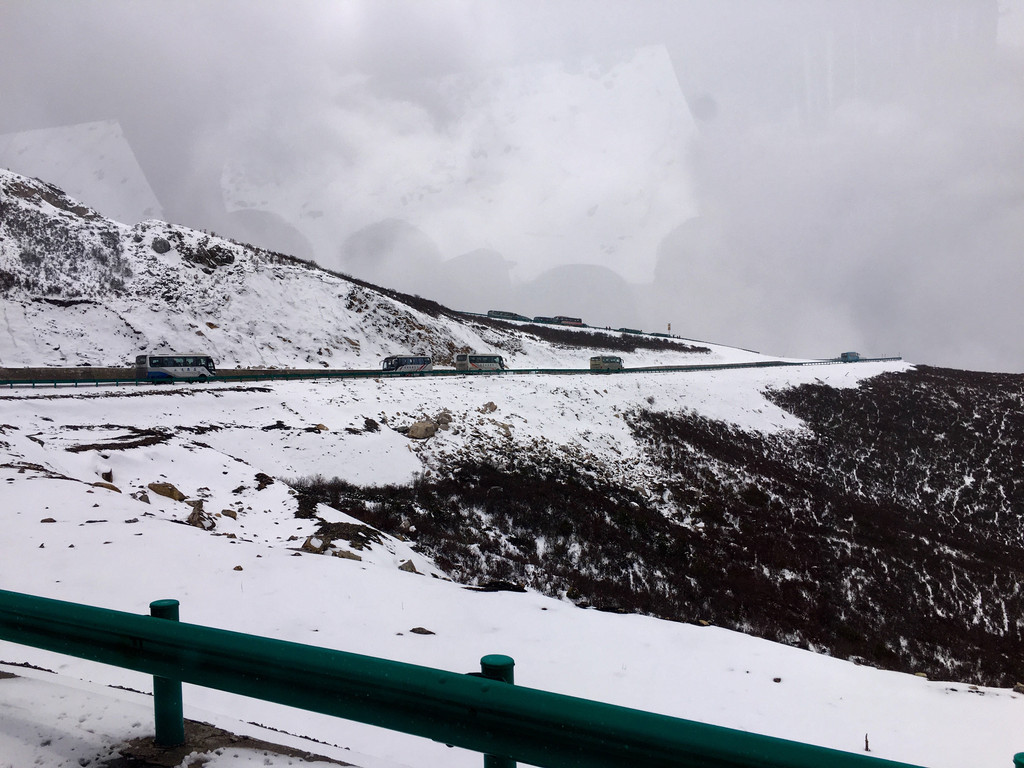 在弥漫的风雪中,汽车沿著盘山公路翻越岷山雪原(车拍.